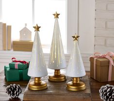 three white christmas trees with gold stars on them