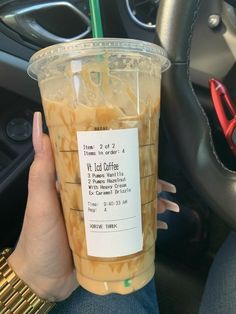 a person holding up a drink in their hand while sitting in a car with the driver's seat behind them