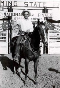 a man riding on the back of a brown horse in front of a white building