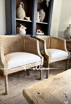 two chairs sitting next to each other in front of a book shelf with vases on it