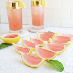 watermelon slices and mint garnish are arranged on a table with gold cups