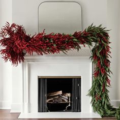 a fireplace decorated for christmas with red and green garland