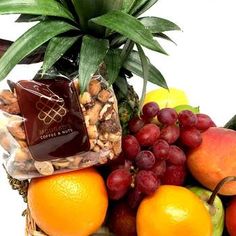 a basket filled with fruit and nuts next to a pineapple