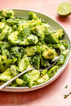 a plate full of broccoli and cucumbers with a spoon in it