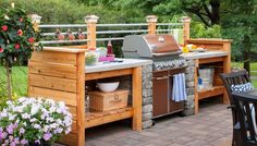 an outdoor kitchen with grill, table and chairs