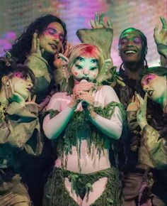 a group of people dressed in costumes and makeup posing for the camera with their hands up