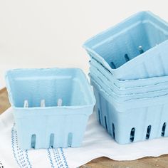 two blue plastic containers sitting next to each other on a white cloth and wooden table