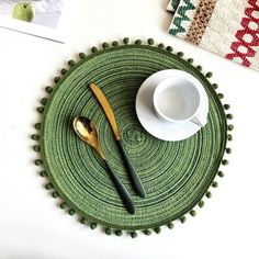 a green place mat with two spoons and a cup on it