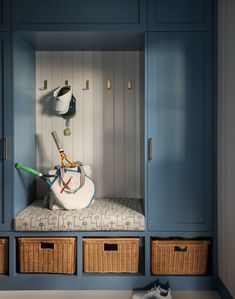 a room with blue cabinets and baskets on the floor, some shoes are sitting in them