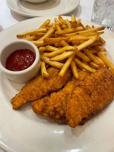 fried chicken and french fries on a white plate with ketchup, dipping sauce