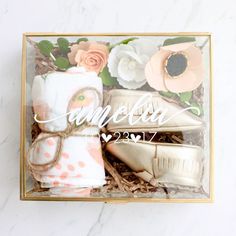 a gift box filled with white and pink items on top of a marble countertop