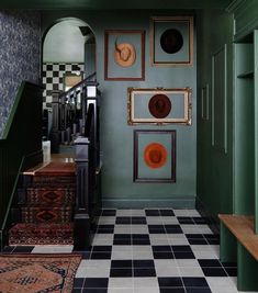 a hallway with green walls and black and white checkered flooring, framed pictures on the wall