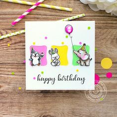 a happy birthday card with animals holding balloons and confetti sticks on a wooden table