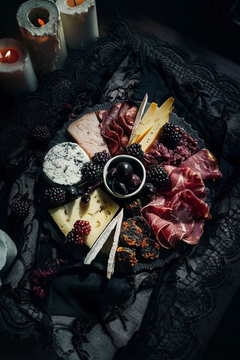 Dark-themed charcuterie board with assorted cheeses, cured meats, blackberries, and olives, placed on a vintage black lace cloth with candlelight for dramatic effect. Charcuterie Lazy Susan, Dark Chocolate Charcuterie Board, Charcuterie Board Dark Aesthetic, Dark Cheese Board, Chic Charcuterie Board, Skeleton Cheese Board, Black Appetizers For Party, Goth Charcuterie Board, Halloween Dinner Aesthetic