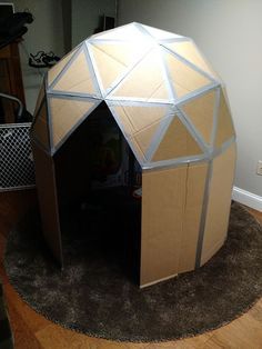 I wanted to make a small play house for the kids, but I didn't want to spend money.  Aside from a $3 pack of hot glue sticks, everything I used here is stuff I already had. I searched online for geodesic domes so I wouldn't have to do all the math myself.  I found a suitable one that people suggested homeless people use as emergency shelter, then scaled it down and added squares on the bottom. For this project, I used: cardboard box cutter pen or pencil ruler hot glue white school ... Cardboard Buildings, Bee Project, Tiger Scouts, Geometric Dome, Cardboard Play, Cardboard Playhouse, Carton Diy, Build A Playhouse, Box Crafts