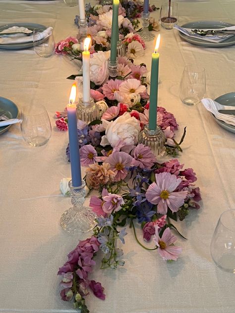 Pink purple blue pastel flower arrangement on dining table with candle sticks and blue ceramic dinner set for birthday dinner party Floral Party Table Decor, Flower And Candle Dining Table Decor, Floral Party Table, Circle Table Set Up, Flower Themed Party Aesthetic, Dinner Party Table Centerpieces, Maximalist Table Decor, Flowers Laying On Table, Candle Light Table Setting