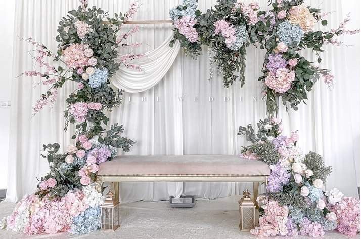 a floral wedding arch decorated with pink, blue and white flowers for the ceremony stage