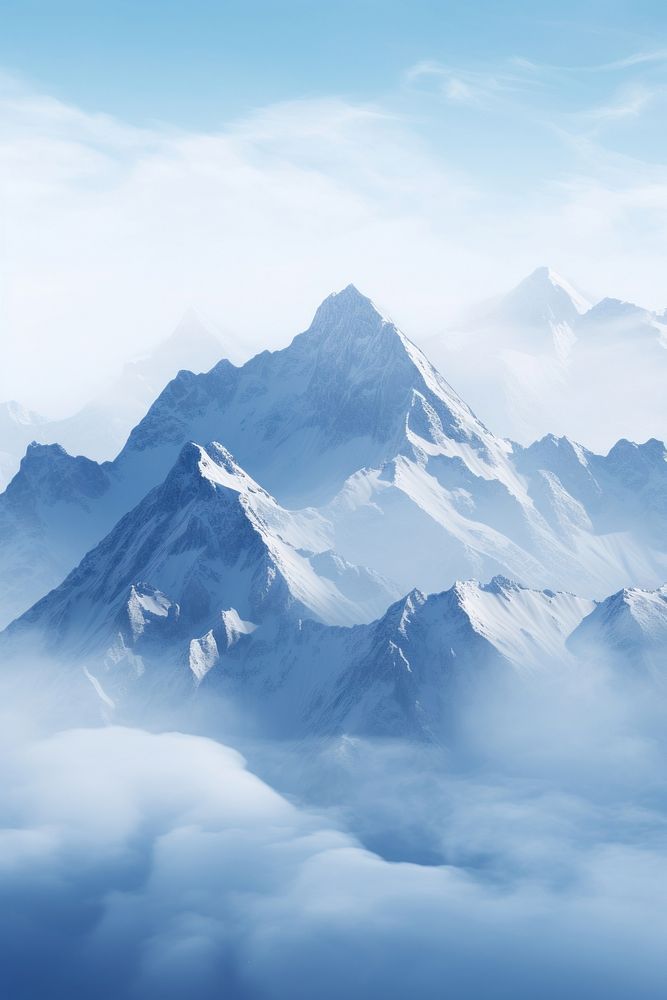 an airplane flying over the top of a mountain covered in fog and clouds with mountains below