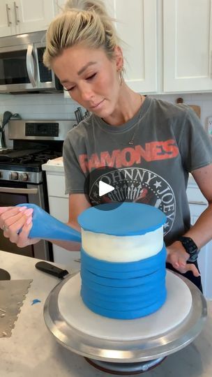 a woman decorating a blue and white cake