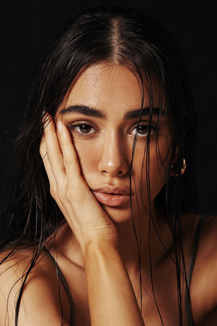 a beautiful young woman posing with her hands on her face