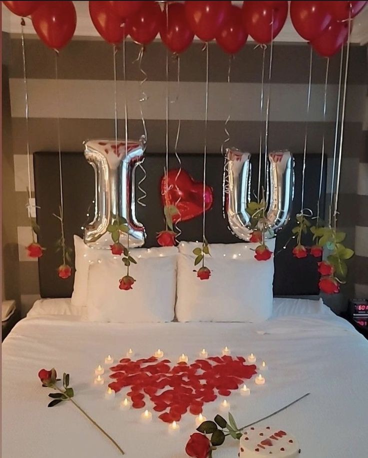 the bed is decorated with red roses and heart shaped balloons for valentine's day