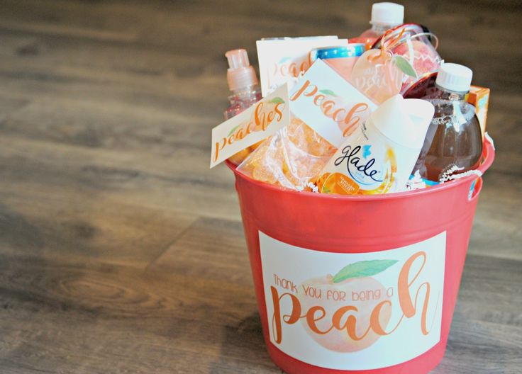 a red bucket filled with lots of different types of food and drinks on top of a wooden floor