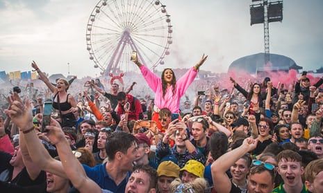 a large group of people at a music festival with their arms up in the air