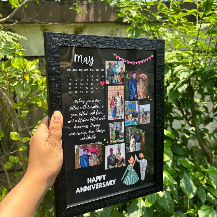 a person holding up a black framed photo with pictures on it that says happy anniversary