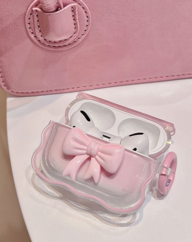 a pink case with a bow on it and an earphone in the shape of a face