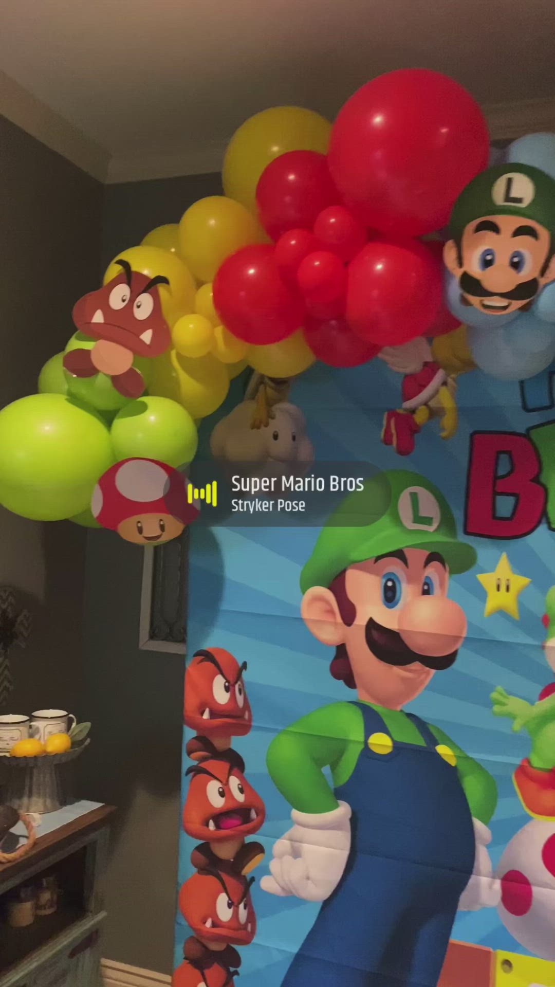 This may contain: mario balloon arch with balloons and super mario bros characters on the wall in front of it