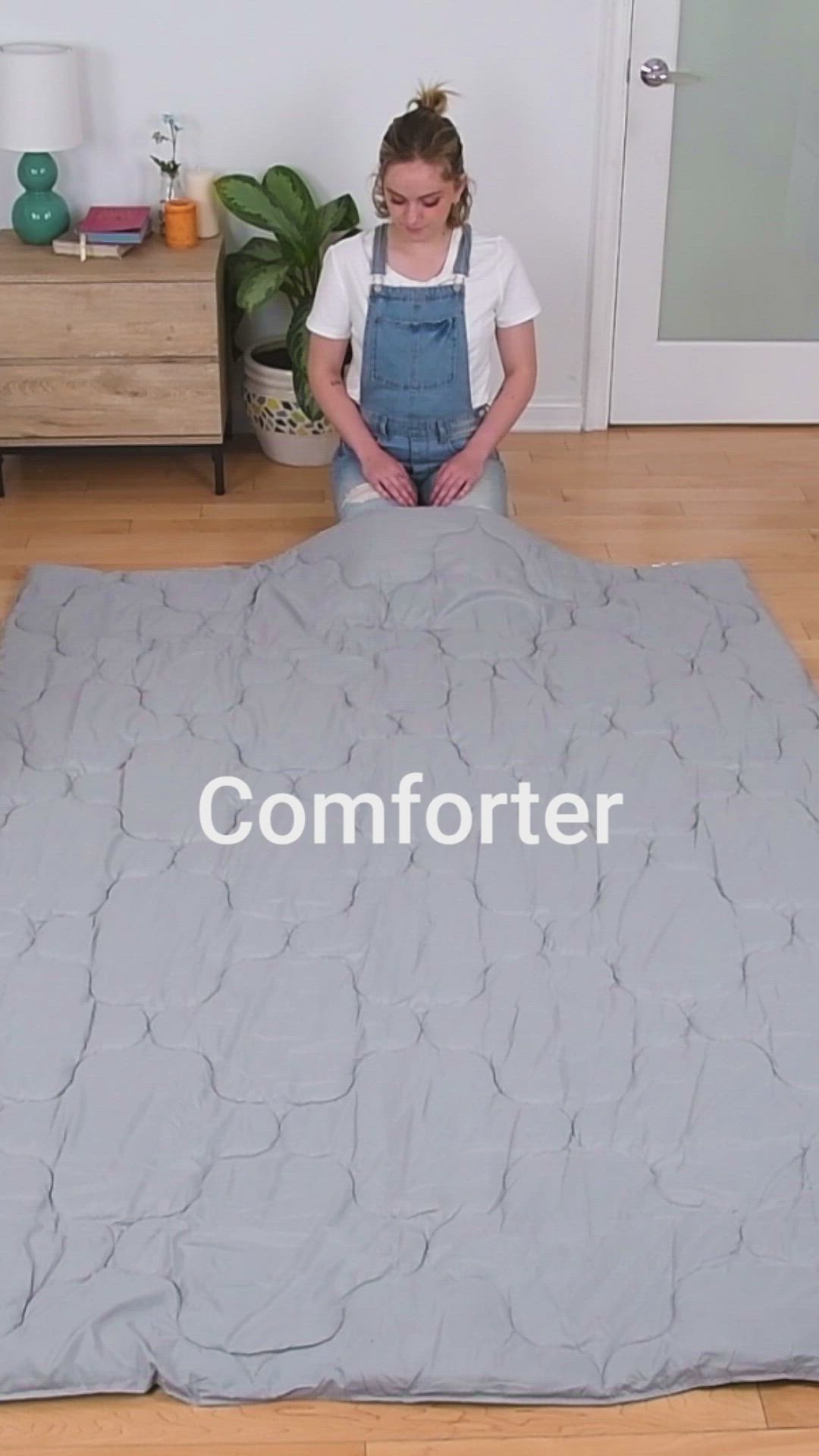 This may contain: a woman sitting on the floor in front of a comforter