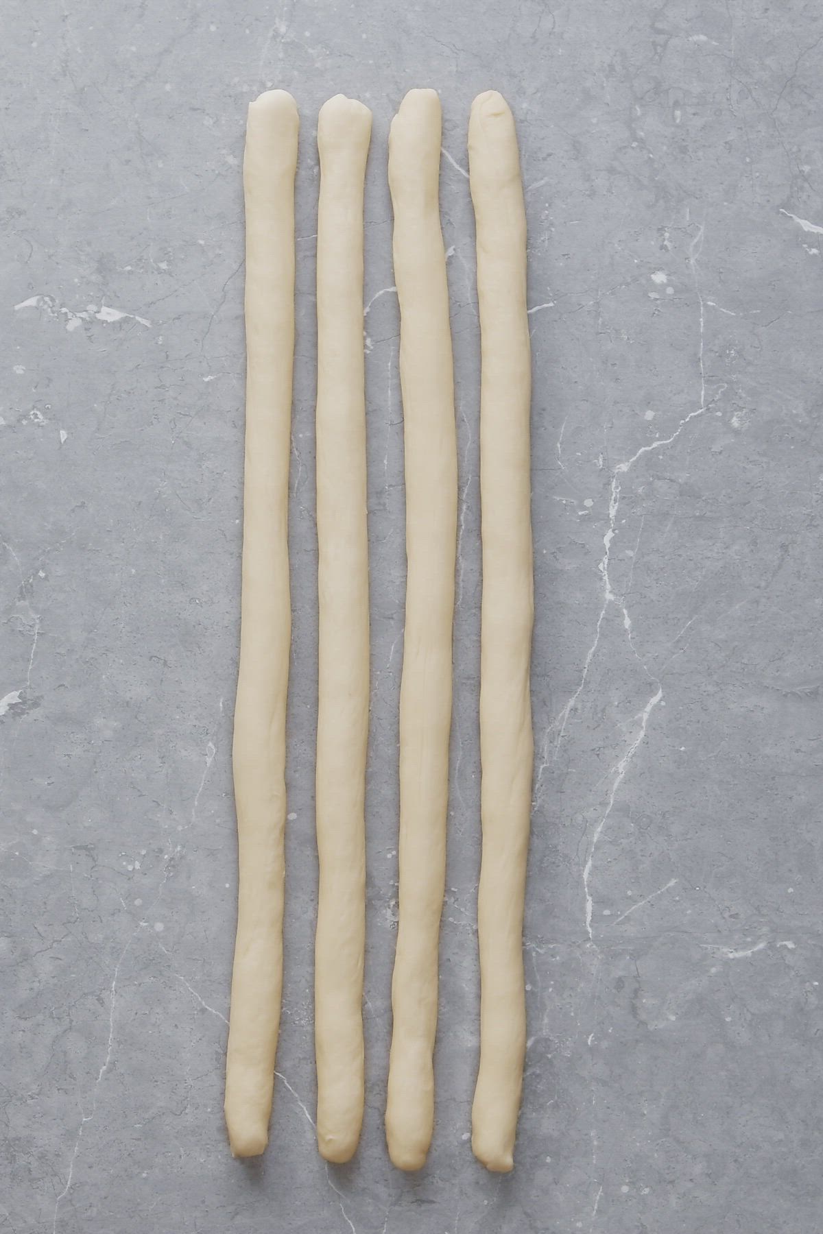 This may contain: three uncooked dough sticks sitting on top of a gray counter next to each other