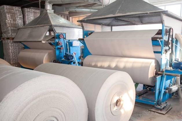 Huge rolls of newsprint paper feeding into a printing press