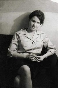 A Black & White photo of a Ulrike Meinhof in her youth, sitting in a couch looking towards the camera.