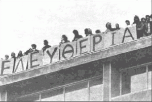 Black & White picture of a students on top of a building, holding a composite sign which spells "Freedom" in greek.