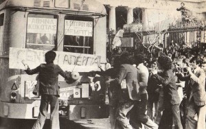 A Black and White photo of students occupying the Polytechnic University standing in front of a Tram. A sign for "General Strike" is displayed.