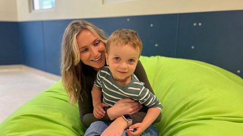 Victoria with her young son Seb both smiling and sitting on a lime green beanbag