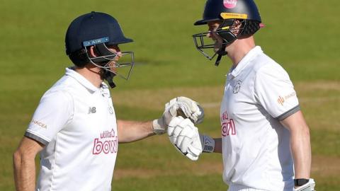 Nick Gubbins celebrates his third Championship century of the season with Liam Dawson (left)