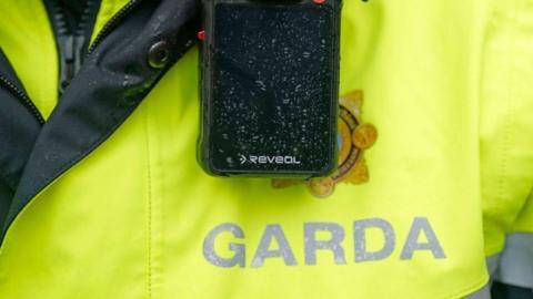 A high viz yellow jacket, with radio attached, worn by an irish police officer