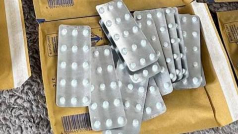 Strips of prescription pills laid out on top of brown envelopes