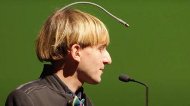 Neil Harbisson side view of him and his antennae, which starts at the back of his head and goes in an arc to above his forehead