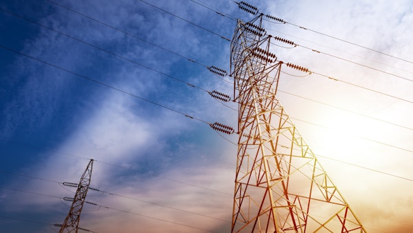 photo from the perspective of looking up to the top of electricity tower pylons with a colorful blue and yellow background in the sky