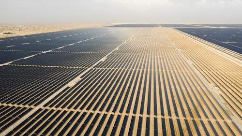 Photo depicts an Aerial view of a landscape with photovoltaic solar panel farm producing sustainable renewable energy in a desert power plant.