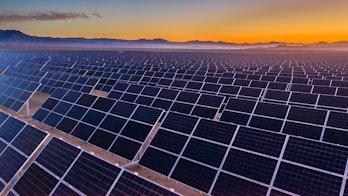 Photo depicts and aerial view of hundreds solar energy panels rows along the dry lands at Atacama Desert, Chile. Huge Photovoltaic PV Plant in the middle of the desert from an aerial drone point of view during sunset