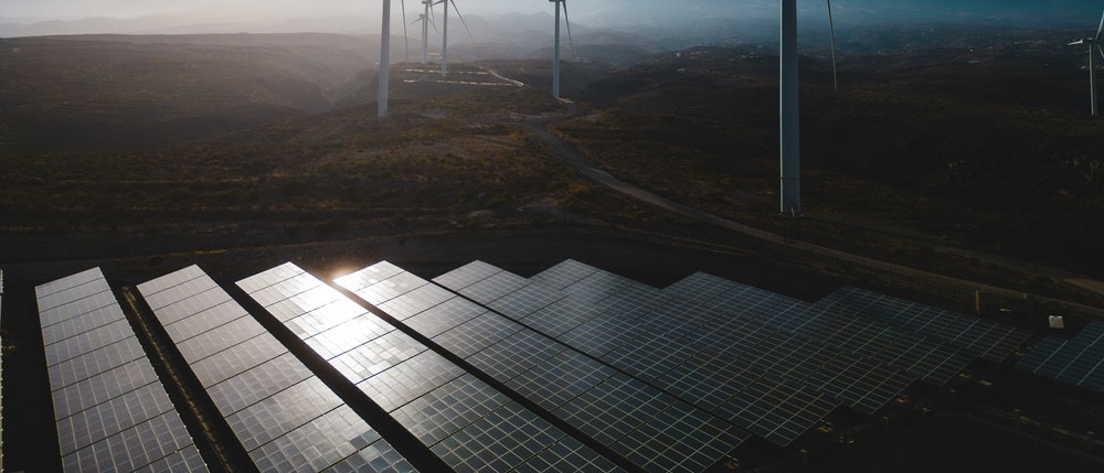 Investment Topic Page Cover Image Windwills In The Background With Solar Panels At The Foreground