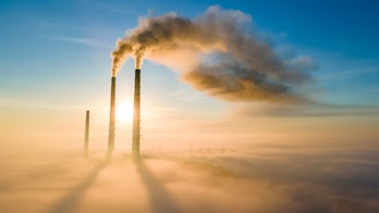 Aerial view of coal power plant high pipes with black smoke moving up polluting atmosphere at sunset.