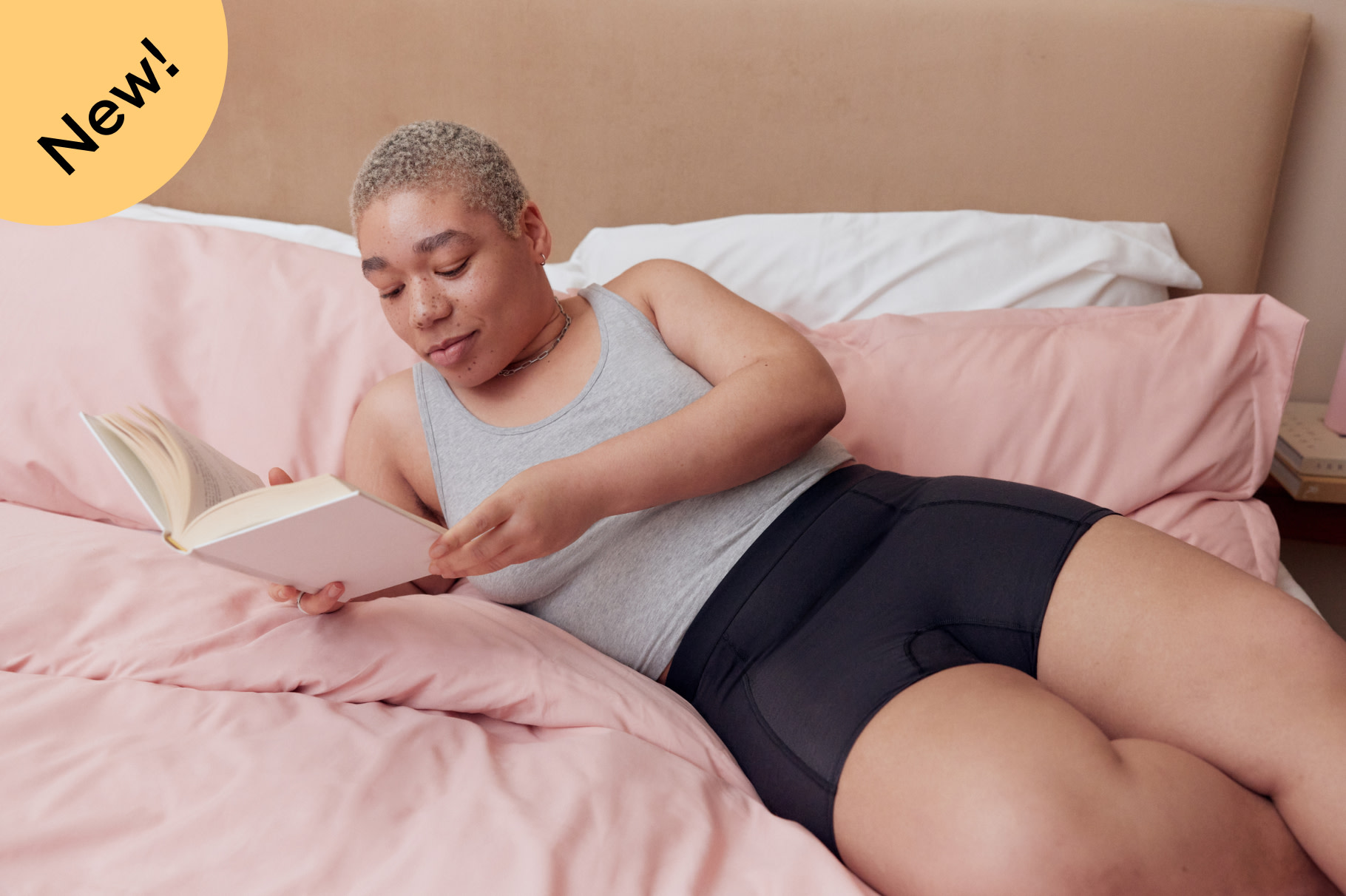 image with a badge on it saying new and showing a person laying in bed wearing thinx overnight boyshorts