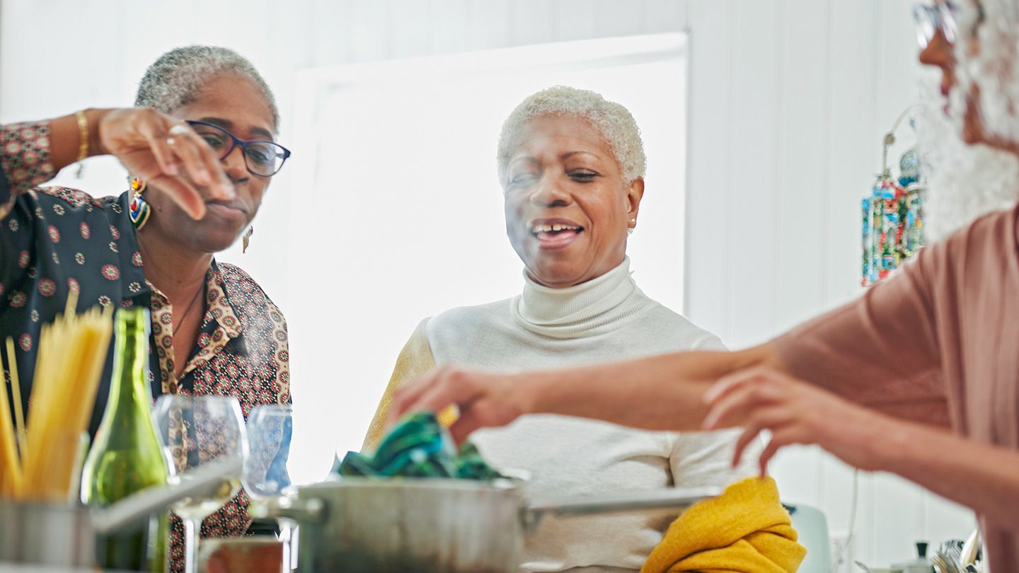 three mature black african american women in kitchen cooking laughing friends