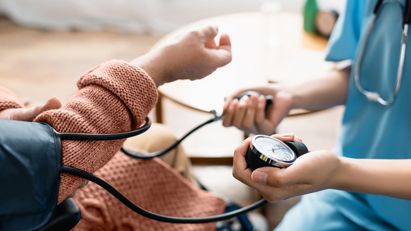 senior woman getting blood pressure taken by visiting nurse