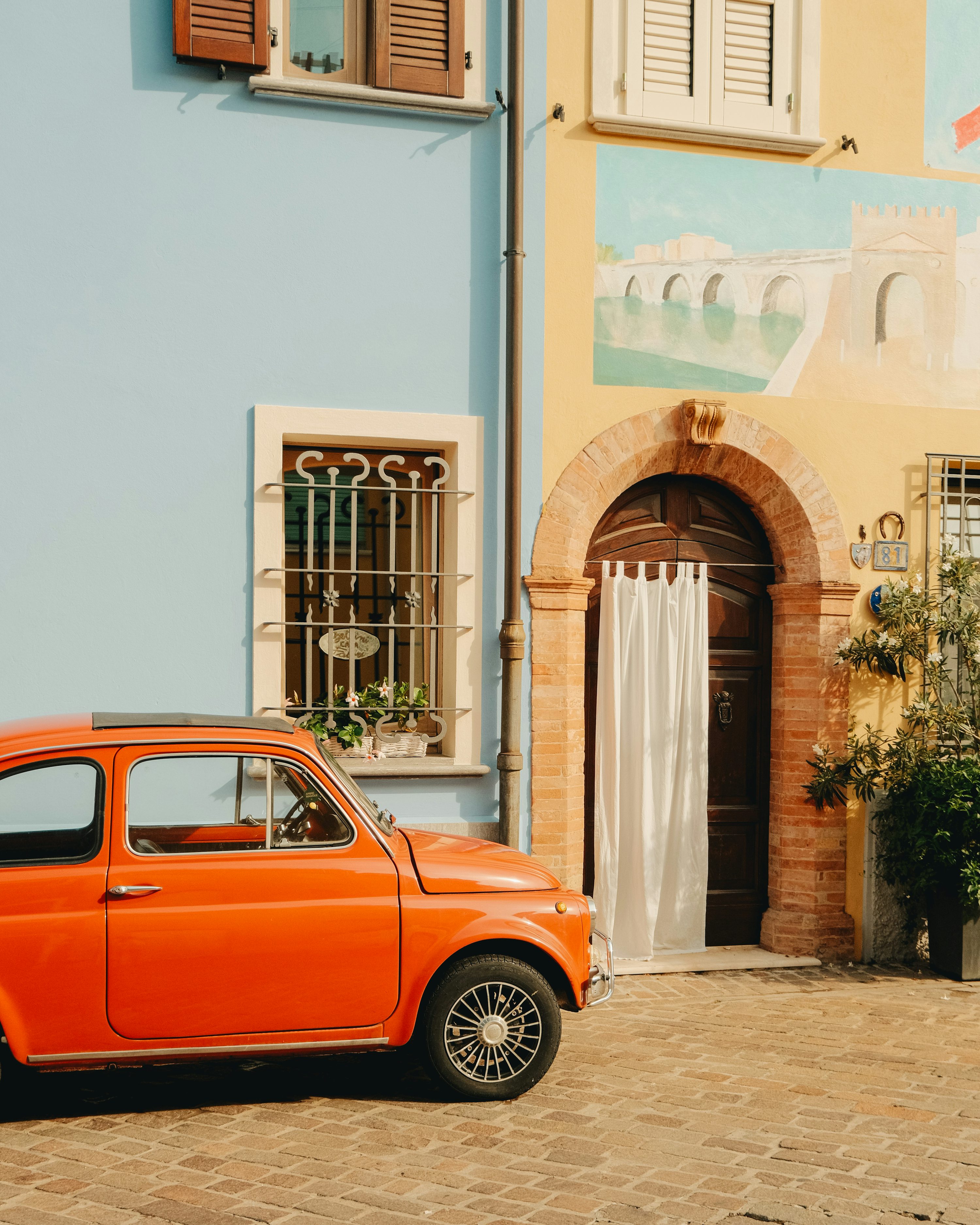 An orange car parked in front of a building